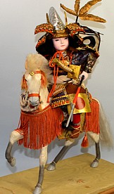 japanese antique doll of a young samurai on white battle hotse