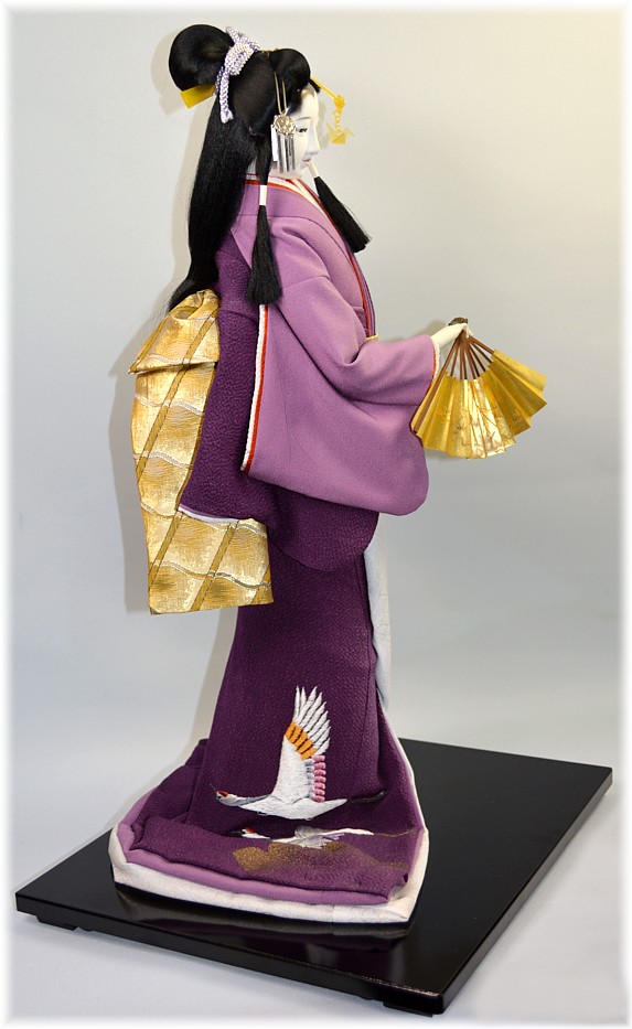japanese traditional doll of a young woman with folding fan in her hand