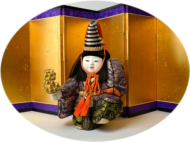 japanaese kimekomi doll of a boy with high hat and with a rattle in his hand
